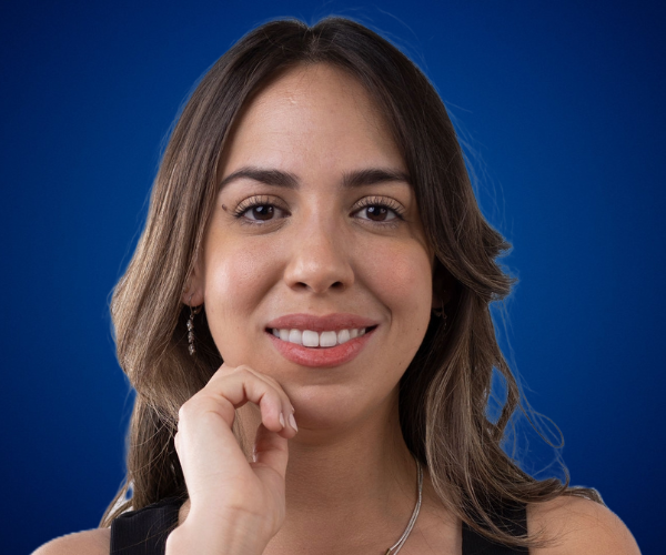 Retrato de Alejandra Tejeda, conferencista y coach ontológico, con un fondo azul.